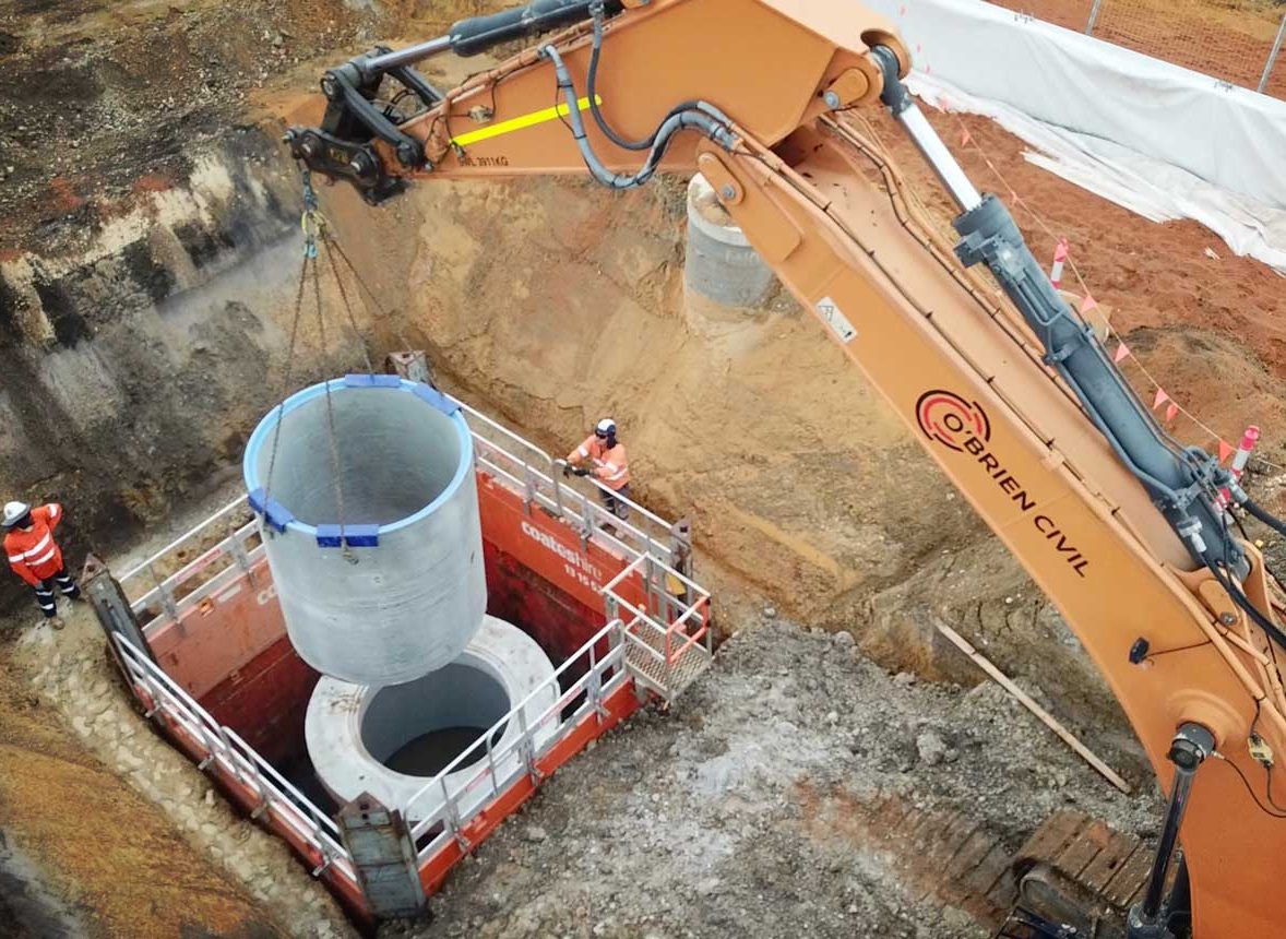 Lifting concrete draining pipe into place at new Midland Railyard construction site